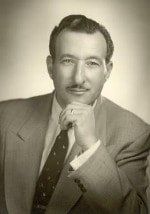 A man in a suit and tie is posing for a black and white photo.