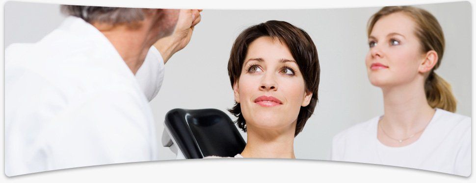 Dentist holding up an x-ray of his patients teeth as she sits in the dentist's chair