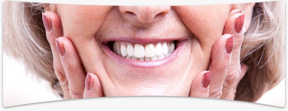 Do you need better fitting dentures? Call us now on 01905 23808 Elderly woman smiling with delight with her hands on her cheeks