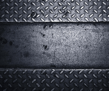 Dark metal plate with diamond tread pattern and a scratched gray center strip