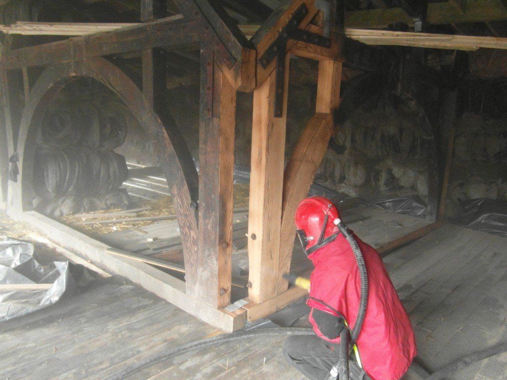 A man in a red jacket is working on a wooden structure.