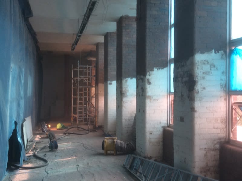 An empty room with a ladder and a vacuum cleaner in it.