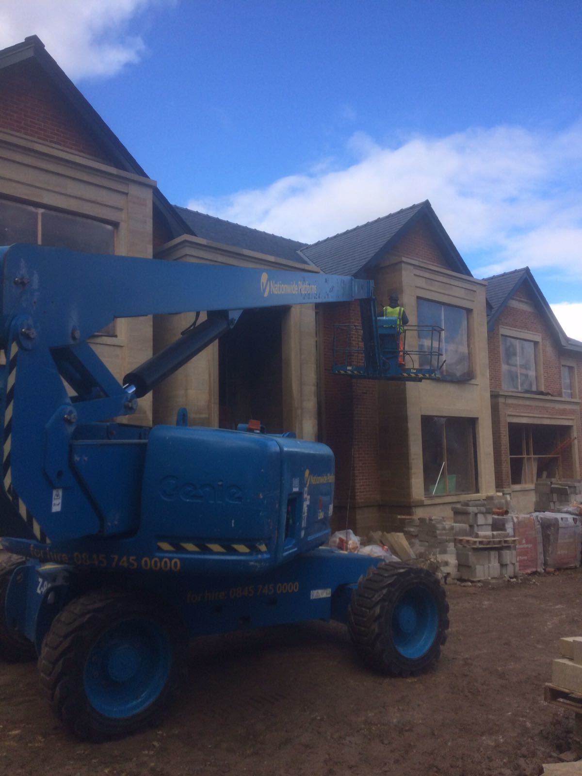 A blue crane is parked in front of a building