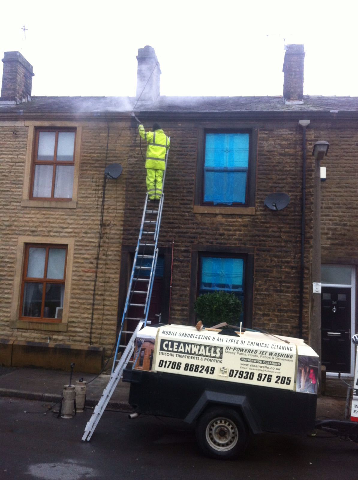 A man standing on a ladder next to a trailer that says clean tile
