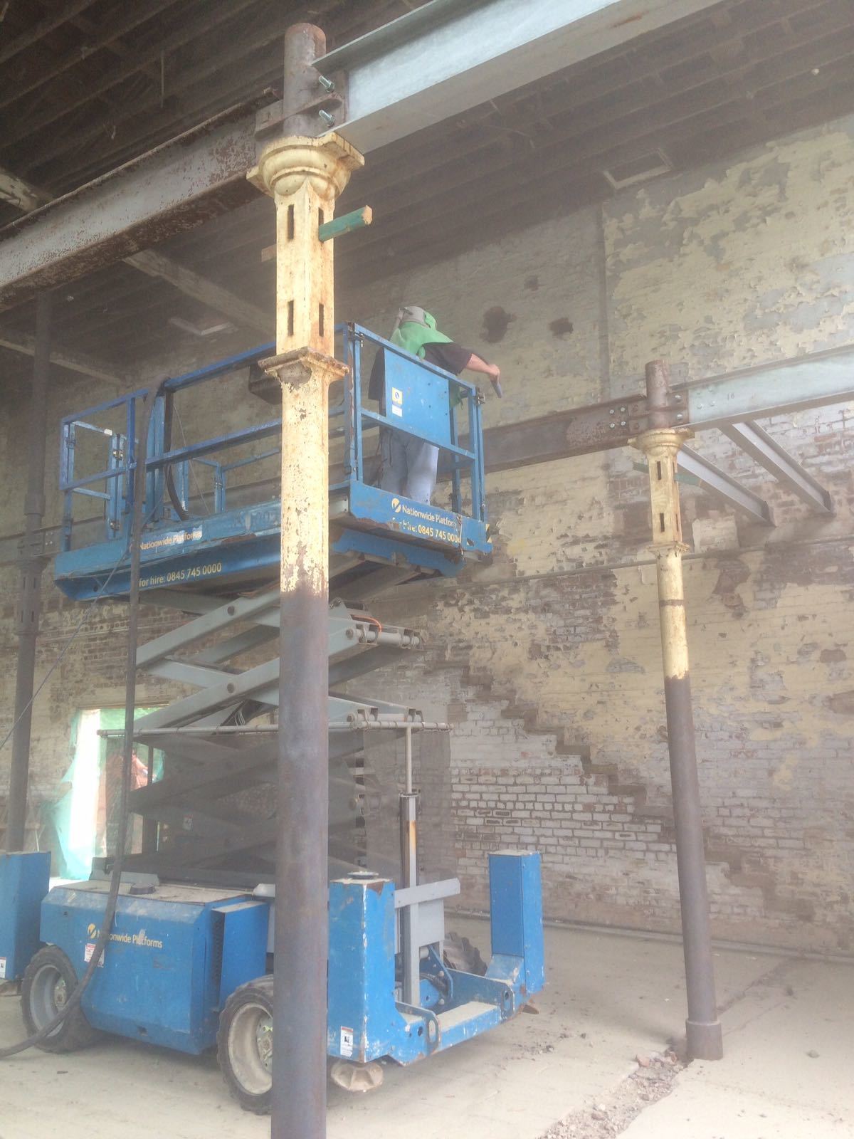 A man is standing on a scissor lift in a building.