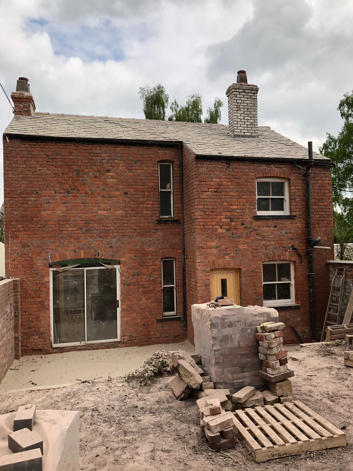 A brick house with a sliding glass door is under construction.
