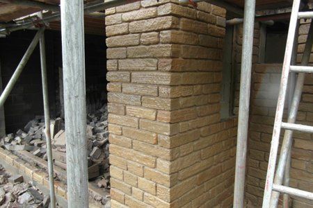 A brick chimney is being built on the side of a building.