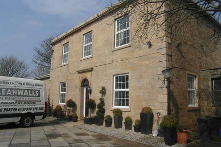 A white leanwalls truck is parked in front of a large stone building