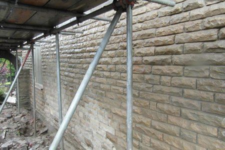 A brick wall with scaffolding around it and a window.