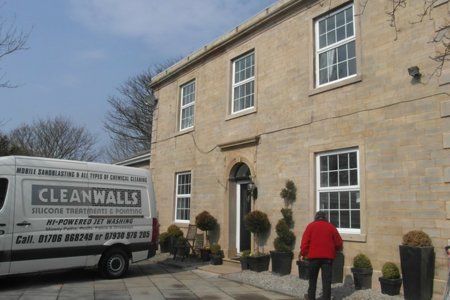 A cleanwalls van is parked in front of a large brick building
