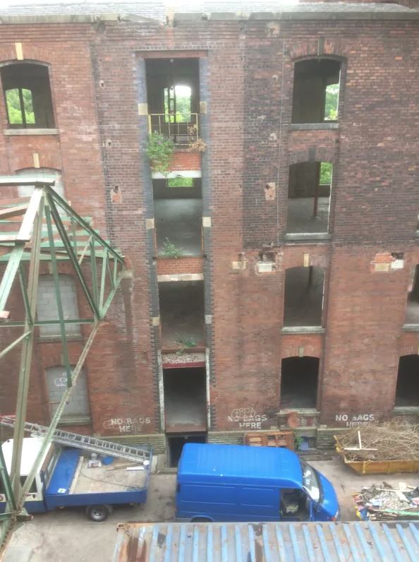A blue van is parked in front of a brick building