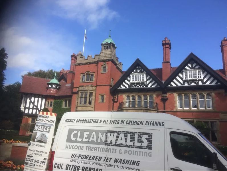 A cleanwalls van is parked in front of a large building