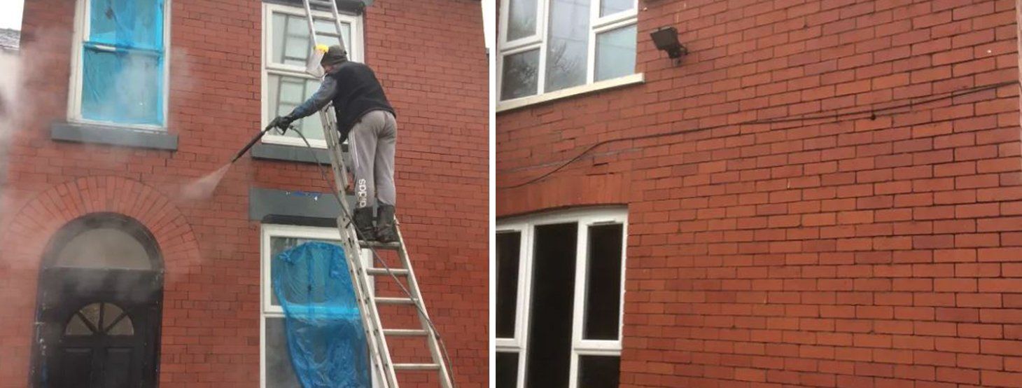 A man is standing on a ladder cleaning a window on a brick building.