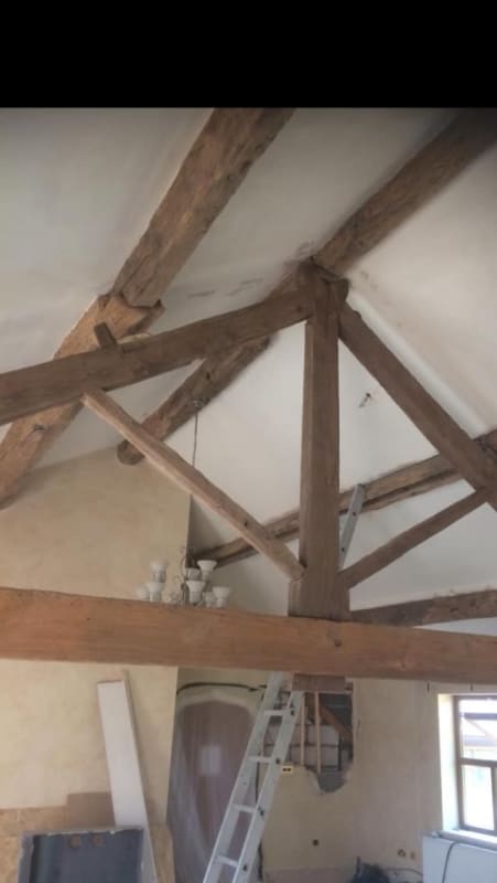 A room with wooden beams and a ladder in it.