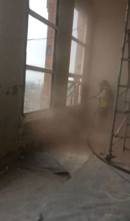 A person is standing in a room with a lot of dust coming out of the windows.
