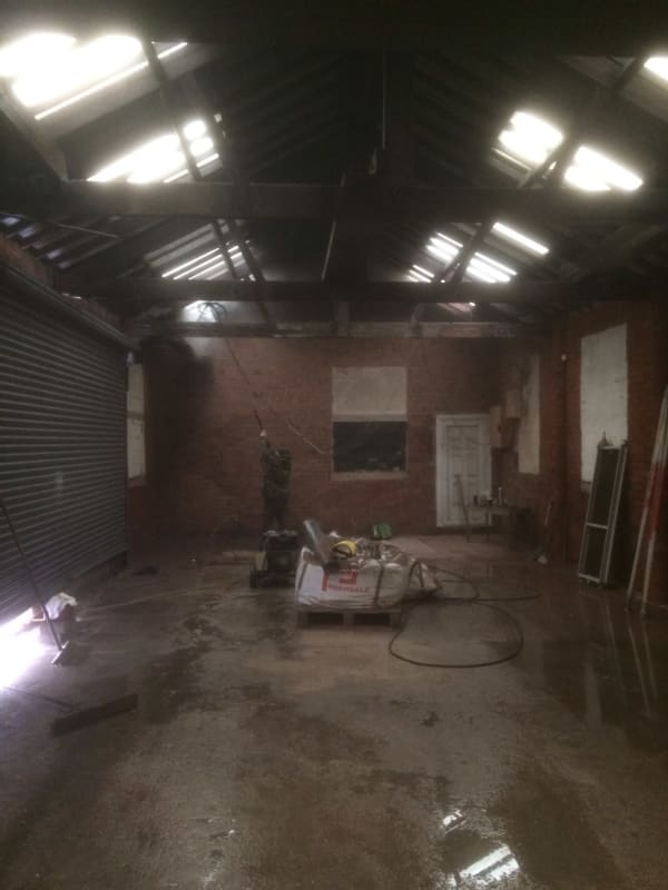 A large empty room with a brick wall and a roof.