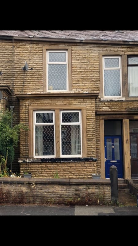 A brick house with two windows and a blue door.