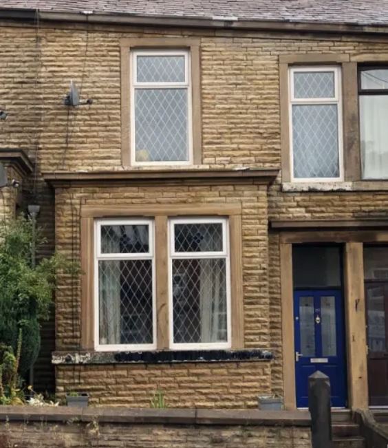 A brick house with two windows and a blue door