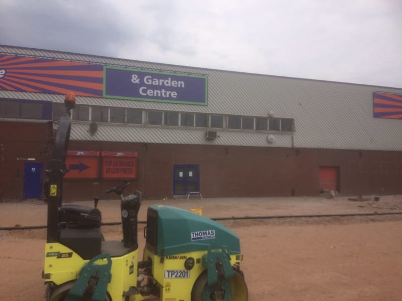A roller is parked in front of a building that says garden centre