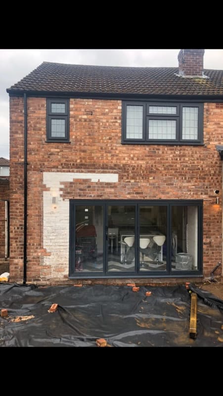 A brick house with black windows and a large sliding glass door.