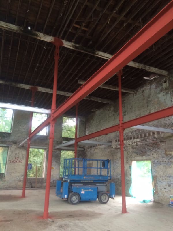 A blue scissor lift is parked in an empty building