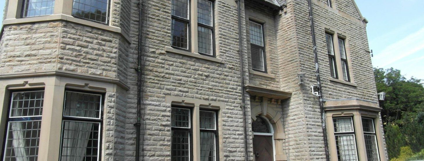A large brick building with a lot of windows and trees in the background.