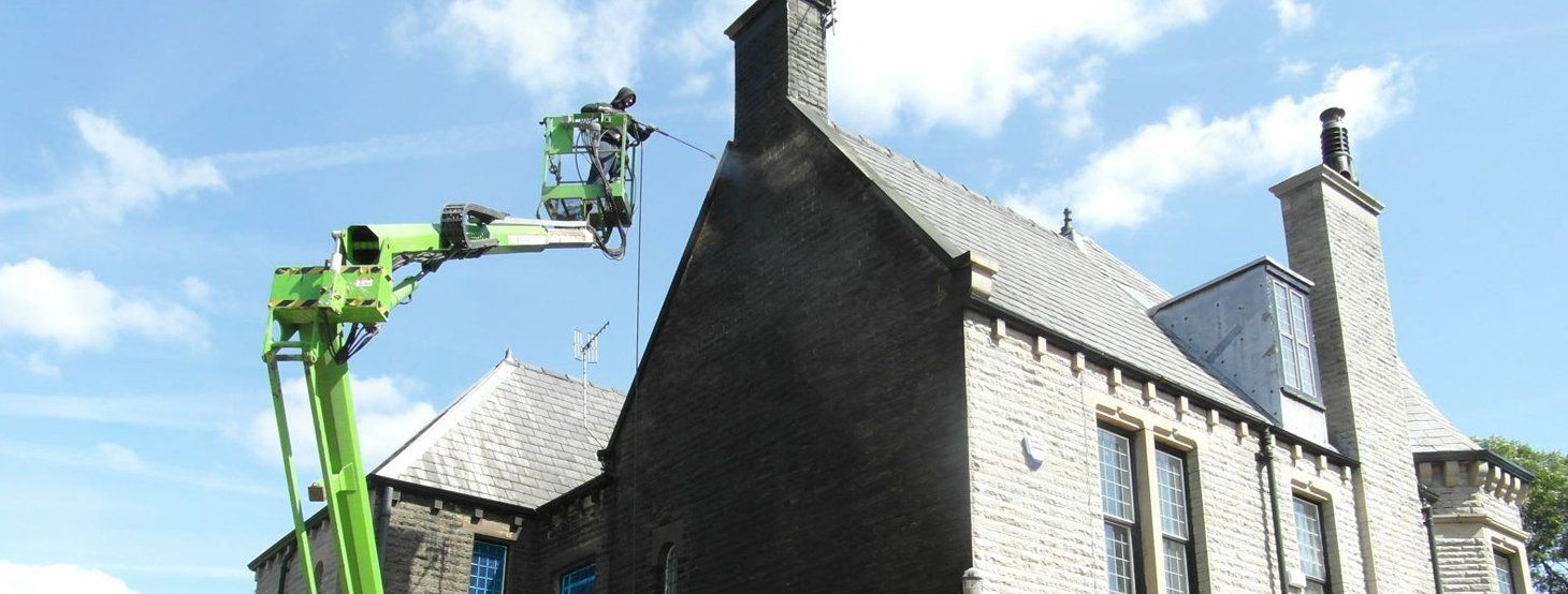 A green crane is sitting on top of a brick building.