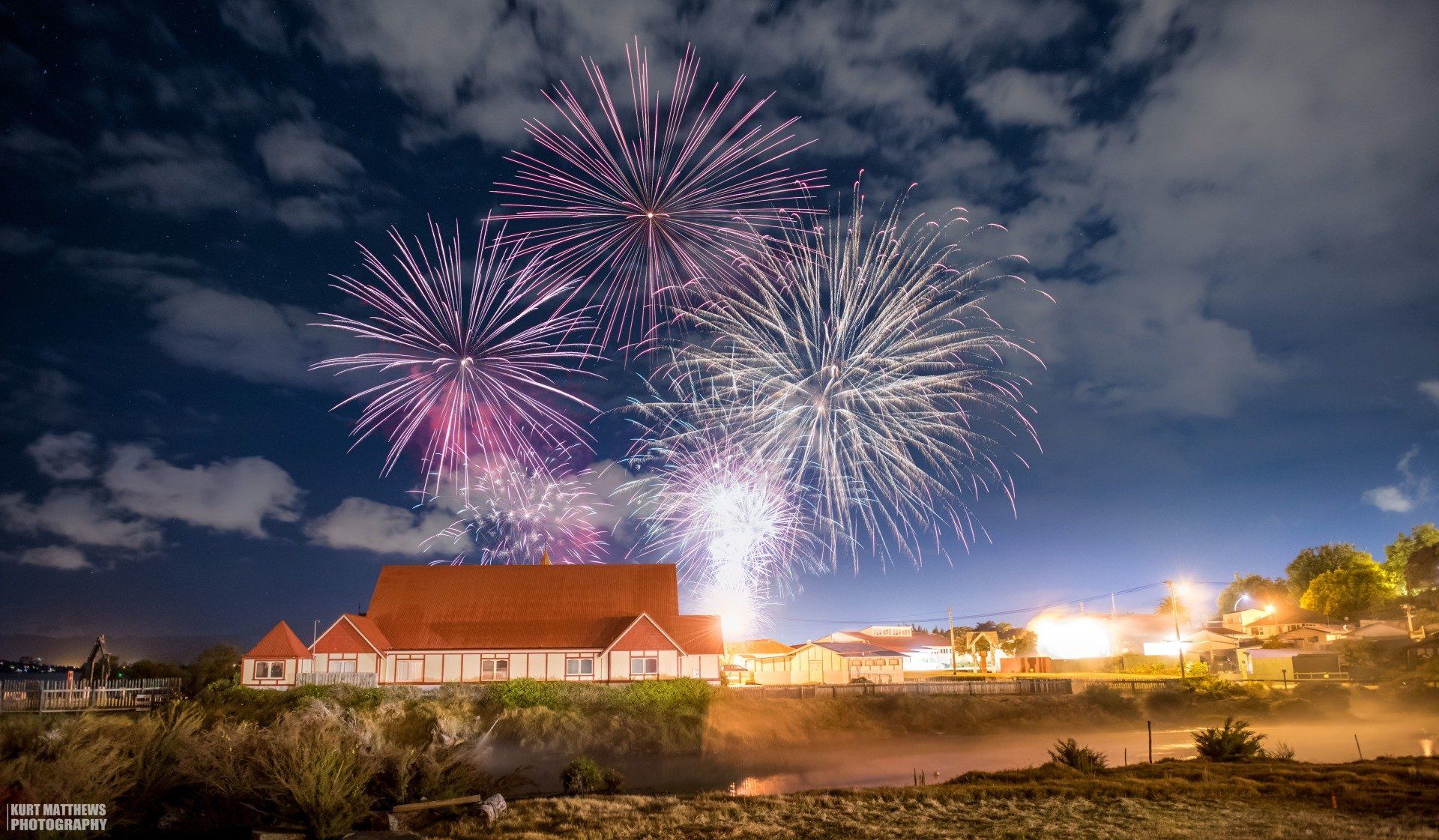 There is a fireworks display in the sky over a building.