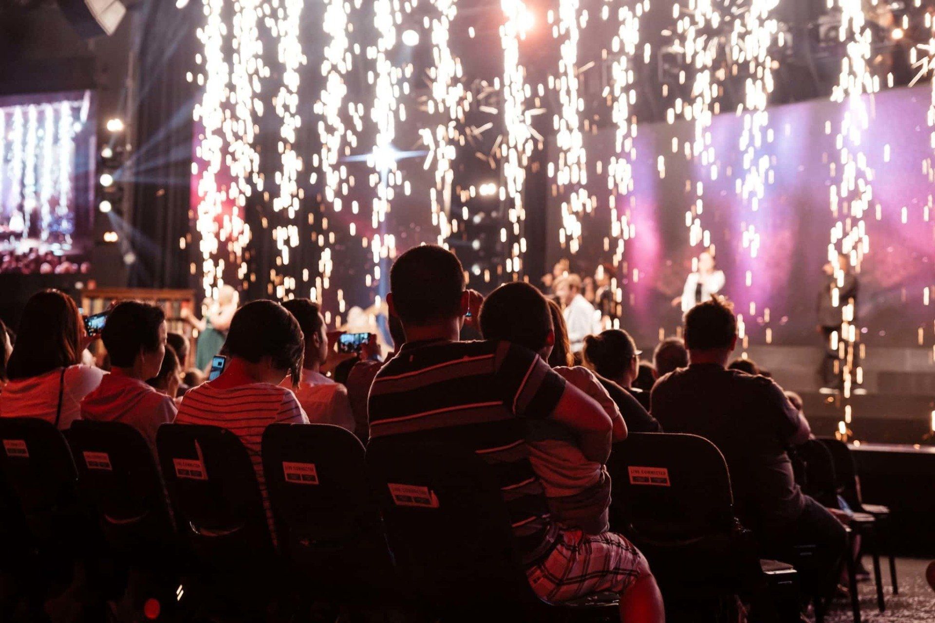 A group of people are sitting in a stadium watching a concert.