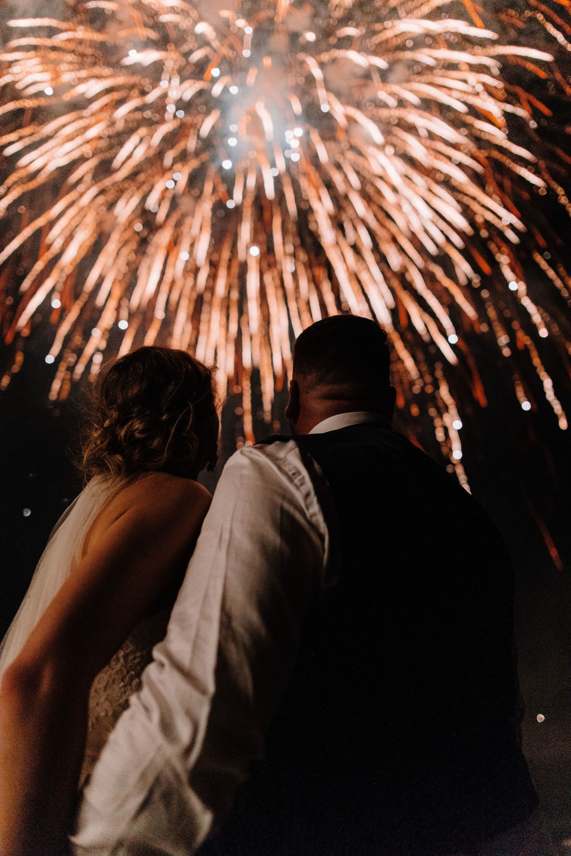 A bride and groom are watching fireworks at their wedding.