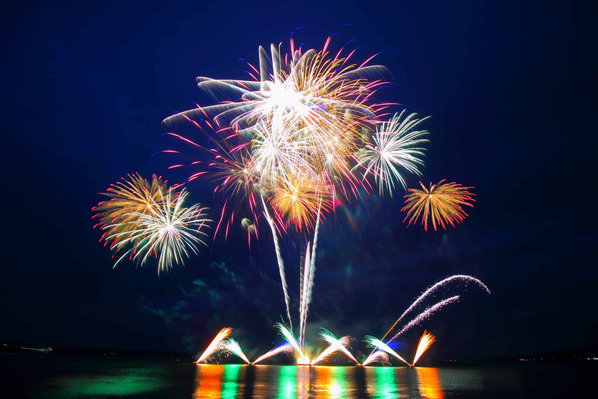 A fireworks display over a body of water at night.