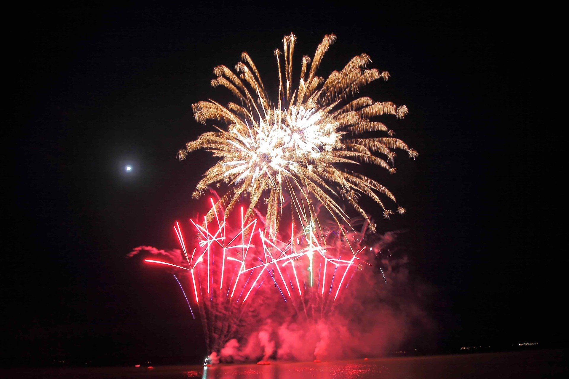 A fireworks display over a body of water at night