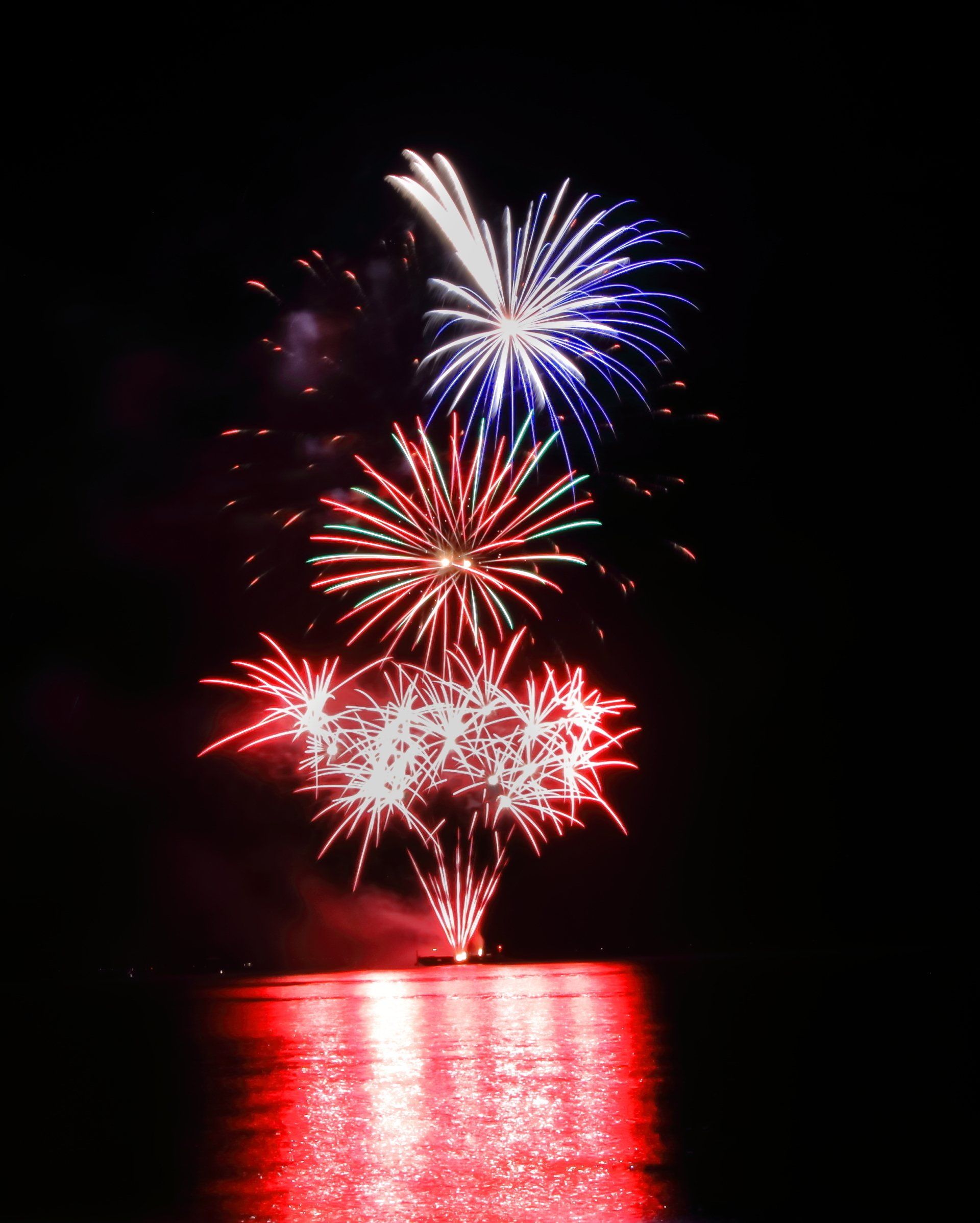 A bunch of fireworks going off over a body of water