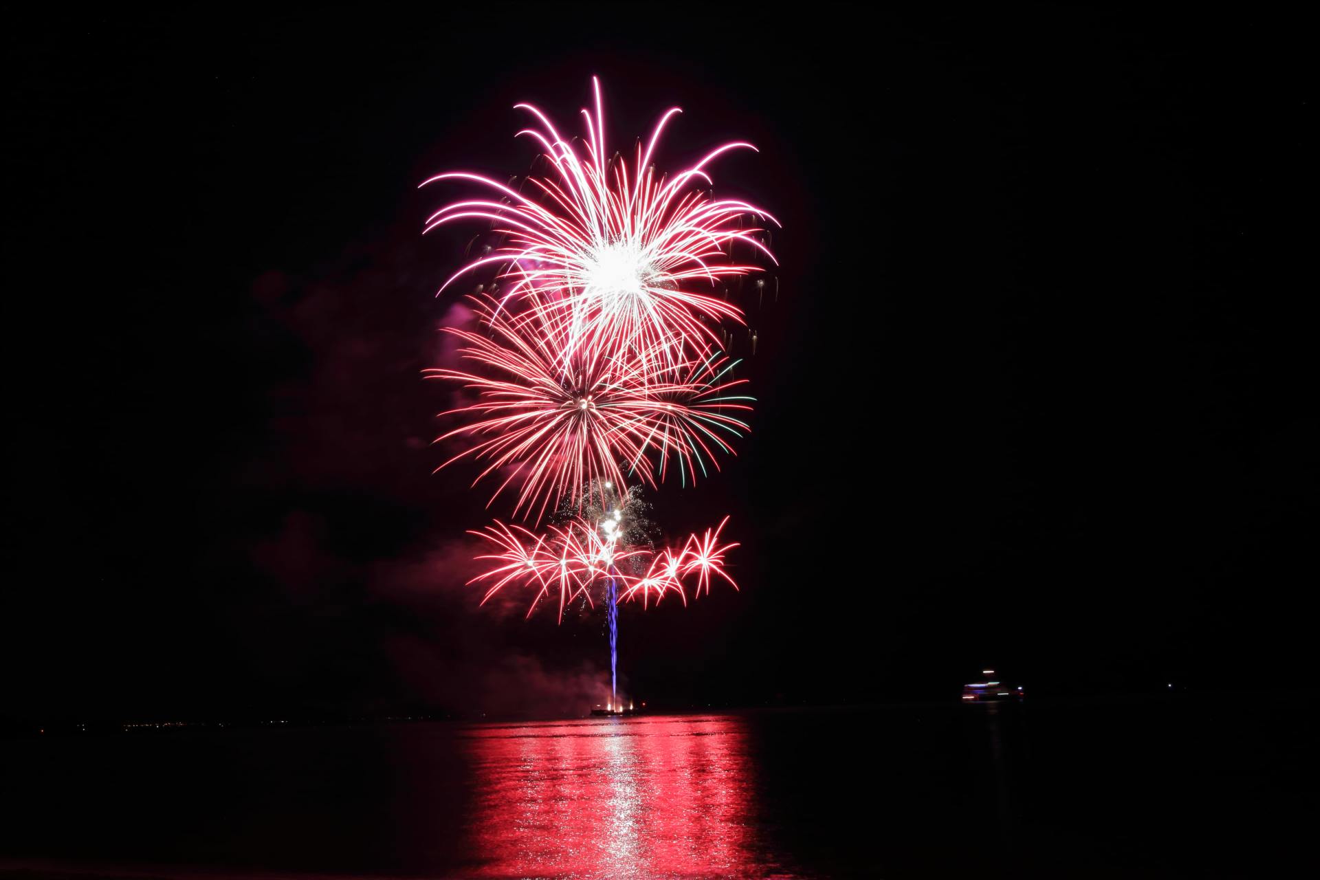 A fireworks display over a body of water at night.