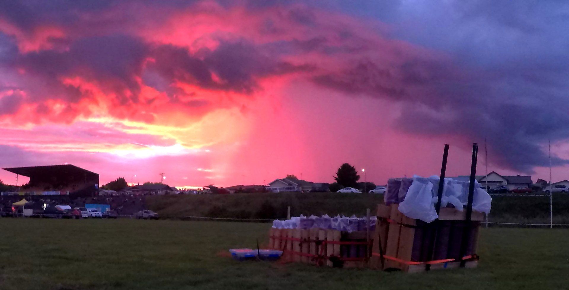 A sunset over a field with a bunch of boxes in the foreground