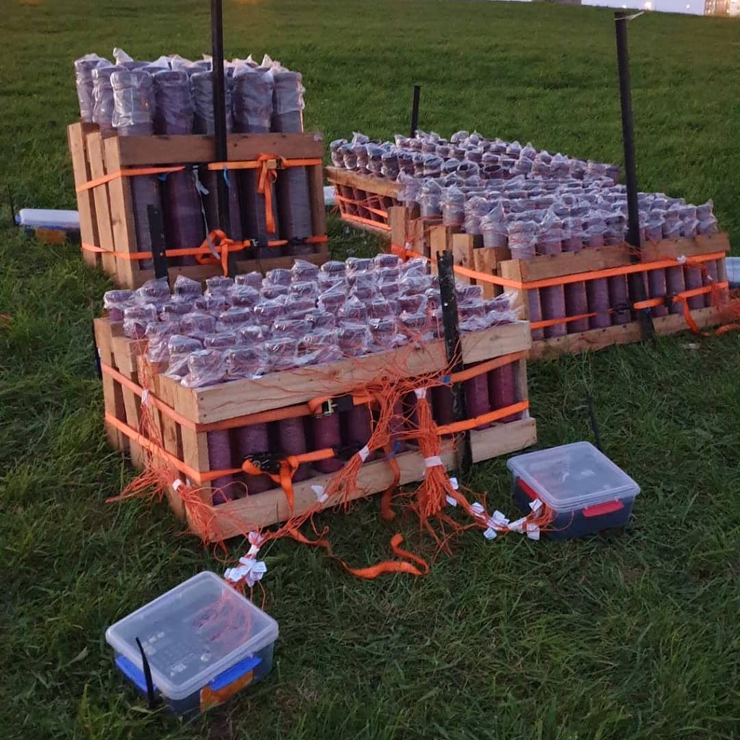A bunch of fireworks are stacked on top of each other in a field ready to Fire