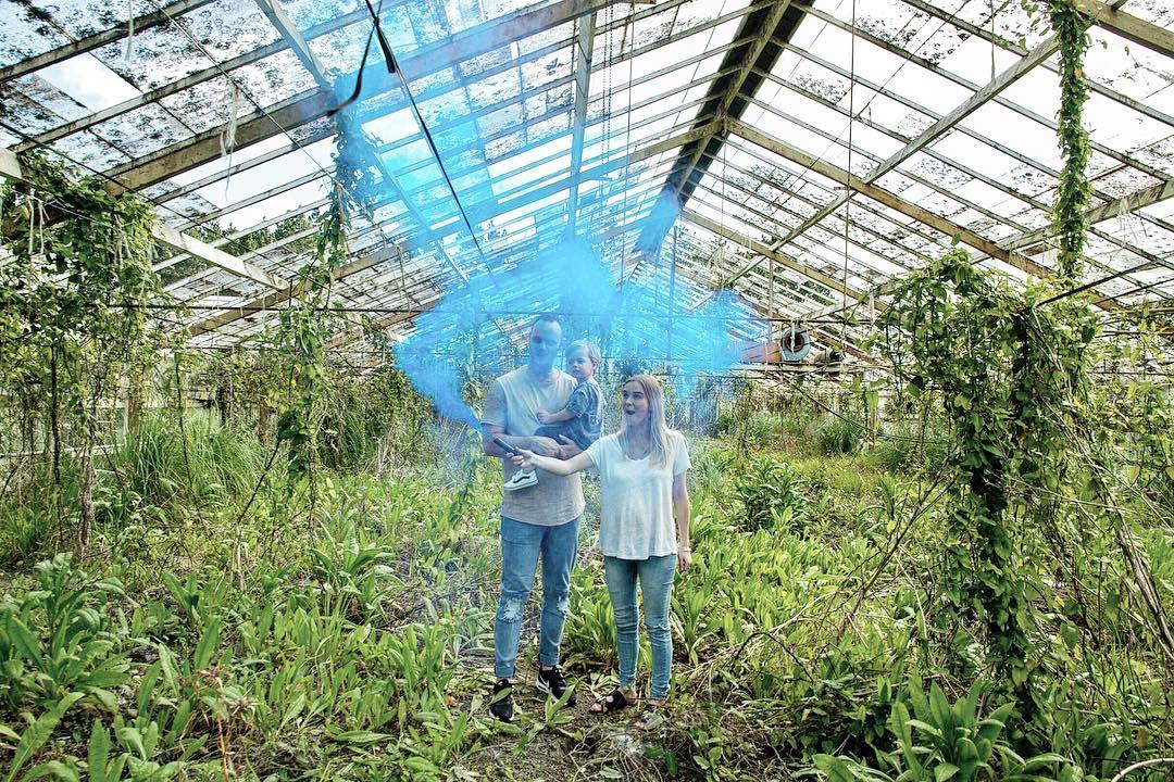 A man and a woman are standing in a greenhouse covered in blue smoke.