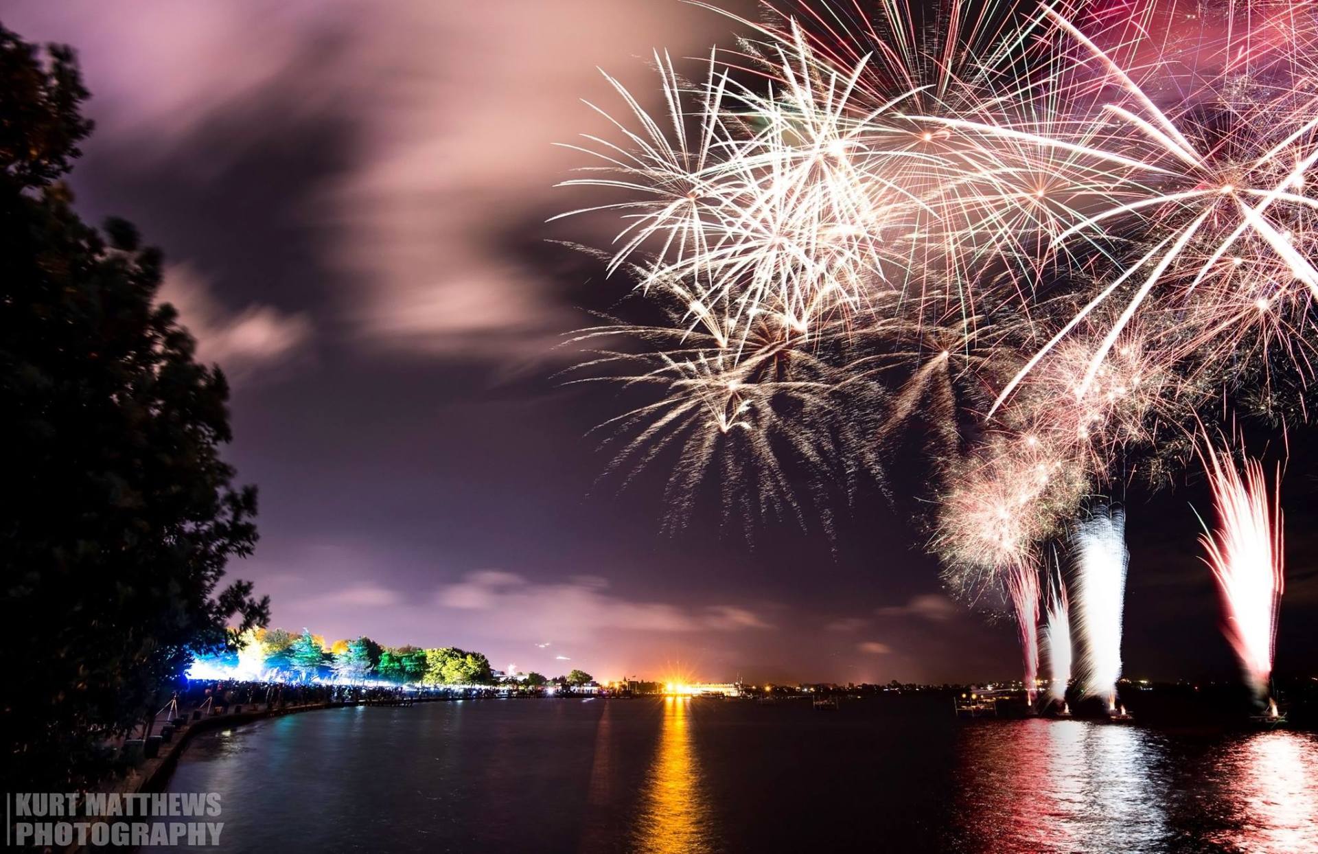 A fireworks display over a body of water taken by kurt matthews photography