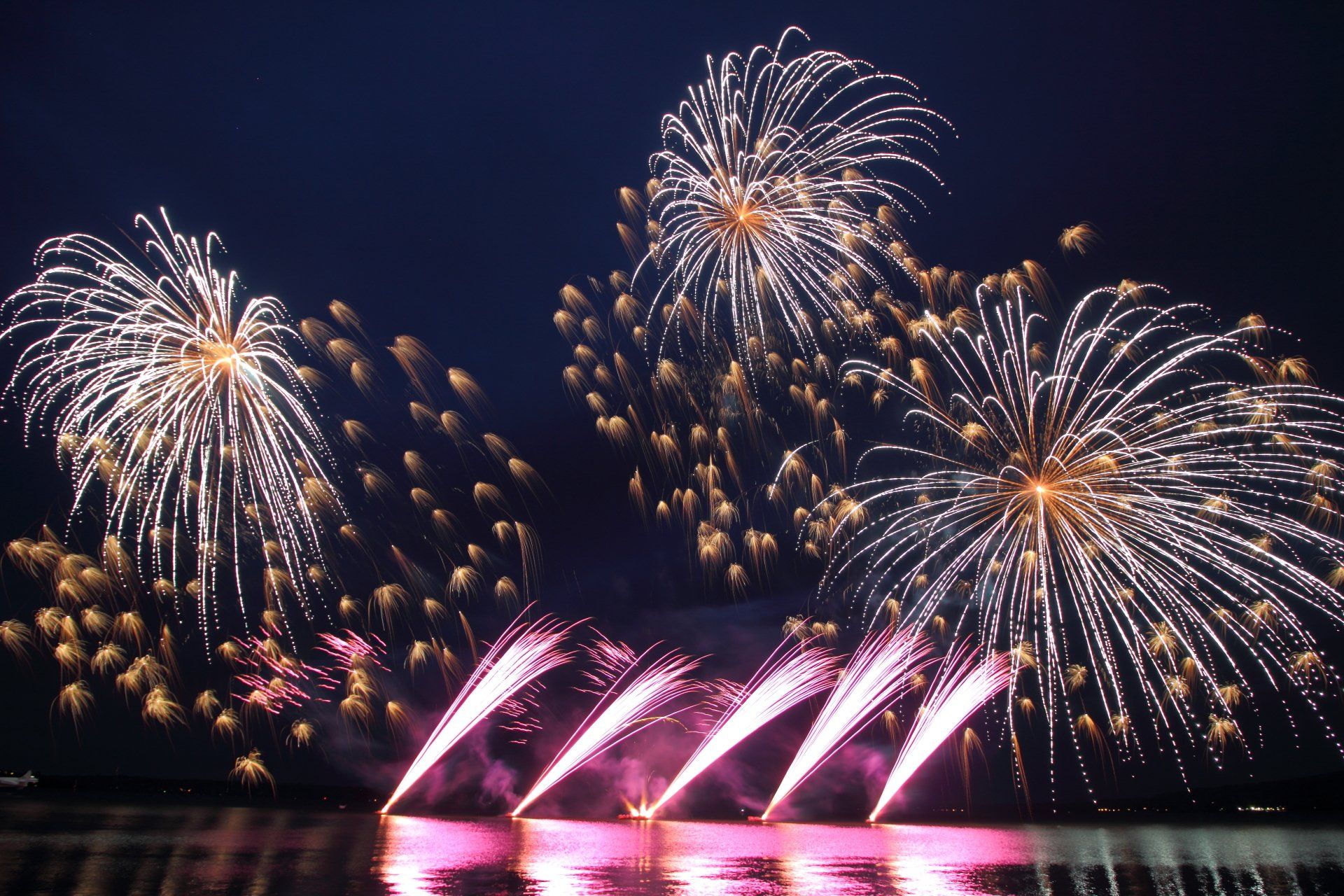 A bunch of fireworks are going off over a body of water