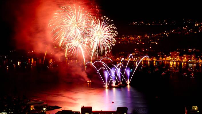 A fireworks display over a body of water at night.