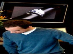 A man in a blue sweater is looking at a diamond ring