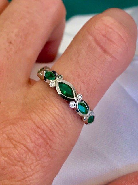 A ring with emeralds and diamonds on a person 's finger