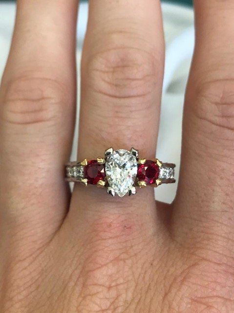 A woman wearing a diamond and ruby ring on her left hand