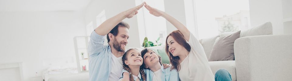 New building residential house purchase apartment concept. Stylish full family with two kids sitting on carpet, mom and dad making roof figure with hands arms over heads