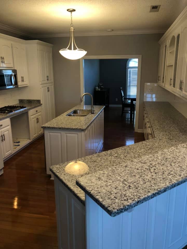 A kitchen with white cabinets and granite counter tops.