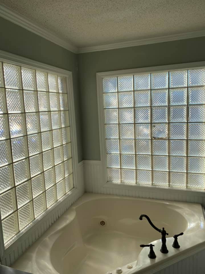 A bathroom with a jacuzzi tub and a window with glass blocks.