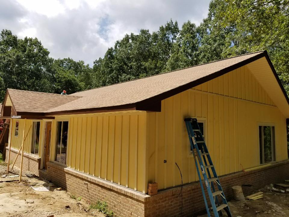 A yellow house with a brown roof is being built.