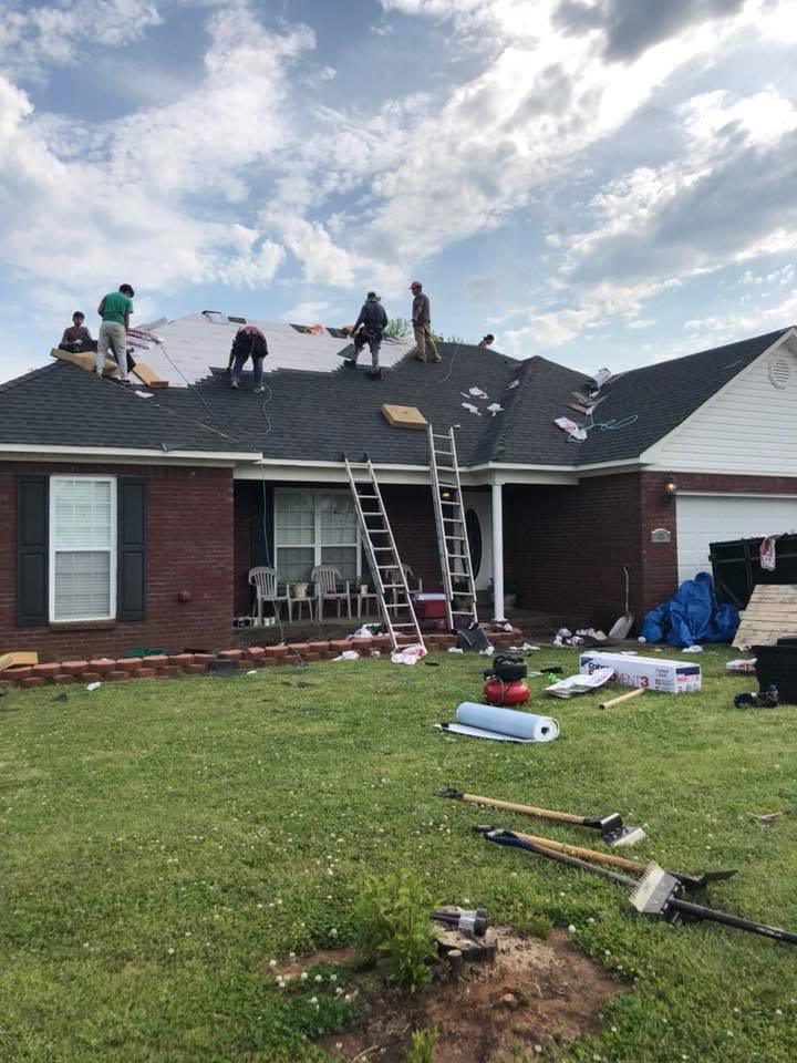 A group of people are working on the roof of a house.