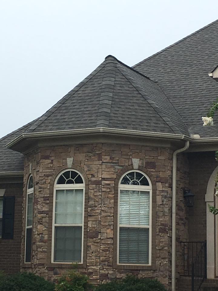 A brick house with arched windows and a gray roof.