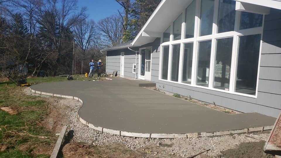 A concrete patio is being built in front of a house.